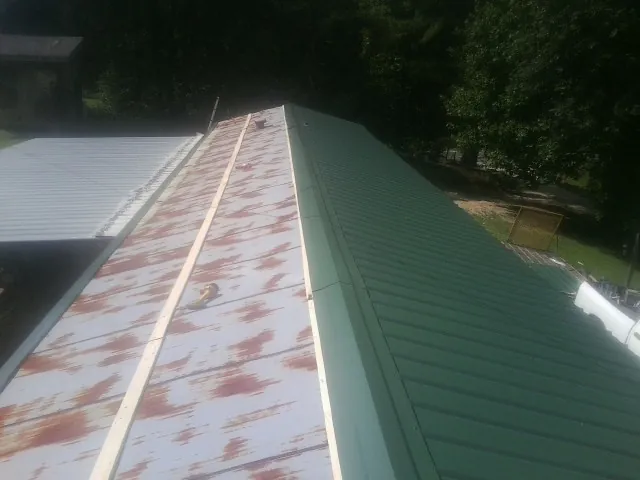 Old rusted panels beside newly installed green metal roofing — Wind Damage Roof Repair by Roofing Brothers in Montgomery