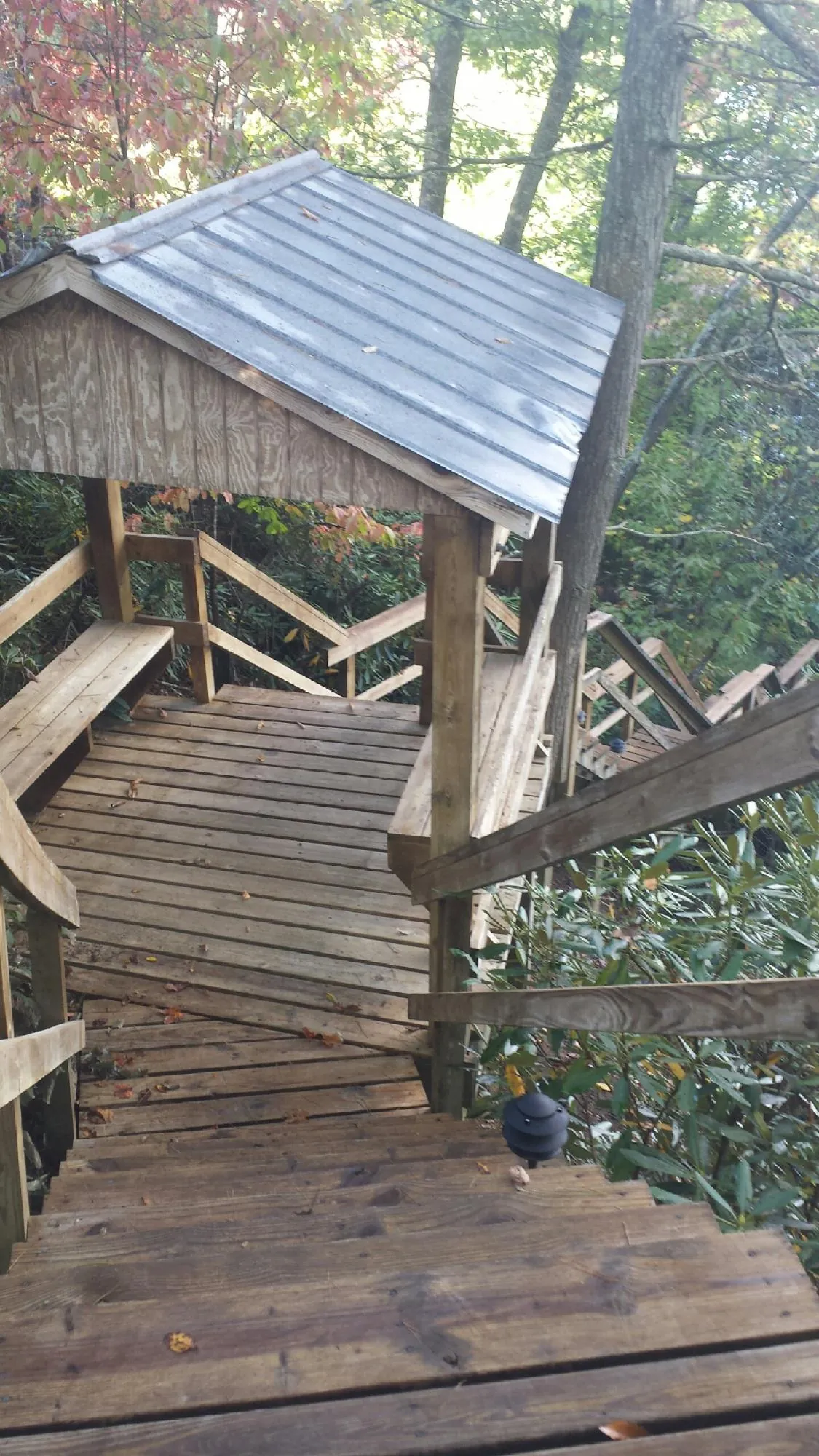 Metal roofed shelter over wooden steps on a wooded walkway — Skylight Repair & Installation work by our crew in Montgomery